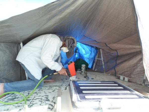 Enclosing an area with tarps and sandblasting difficult to grind areas on deck.