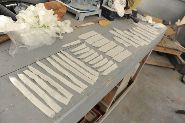 Fiberglass cloth cut to length and arranged in the order in which they'll be epoxied in place.