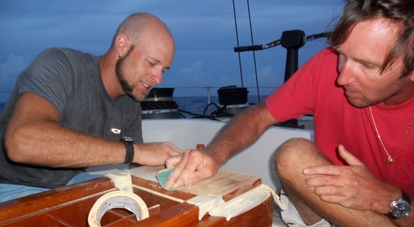 Boat work never ends, even while on a passage! Nicolas and I sanding the teak cockpit table on a calm night at sea.