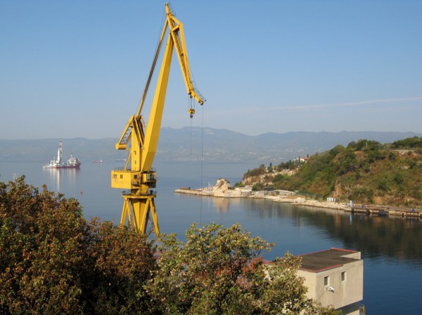 The morning sun rises over the shipping port of Rijeka as I pedal south.